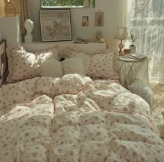 a bed with white and pink comforters in a bedroom next to a window,