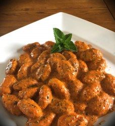 a white plate topped with meatballs covered in sauce and garnished with a green leaf