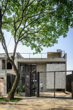 a building with a tree in front of it and a fence around the entrance area