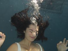 a woman under the water with her hair blowing in the wind and making peace signs