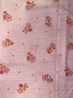 a pink and white checkered fabric with small red flowers on the bottom half of it