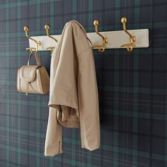 a coat rack with two coats hanging from it's hooks and a purse on the wall