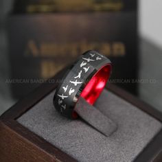 a black and red ring with white doves on it in a wooden display case