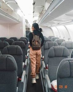 a woman standing on an airplane aisle with her back to the camera