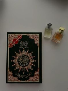 an open book sitting on top of a table next to two perfume bottles and a candle