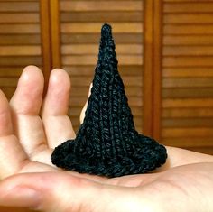 a hand holding a small crocheted black object in it's left palm