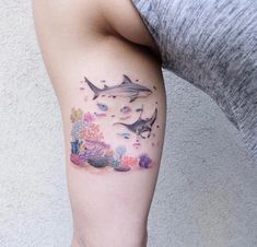 a woman's arm with a shark and coral tattoo on the left side of her leg