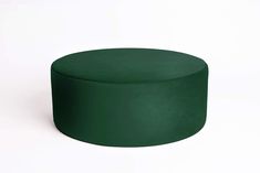 a green round ottoman sitting on top of a white floor