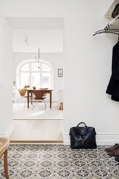 an entry way with a coat rack, bench and shoes on the floor in front of it