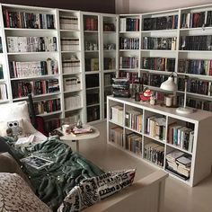 a living room filled with lots of bookshelves next to a couch and coffee table