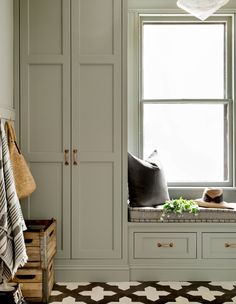 a window seat in the corner of a room with white cupboards and pillows on it