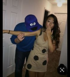 a man and woman dressed up as cookie monster and lady in dress with arms around each other