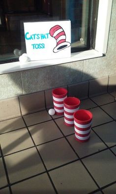 three red and white striped cups sitting on top of a tiled floor next to a sign