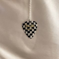 a black and white checkered heart shaped necklace with the word'love'written on it