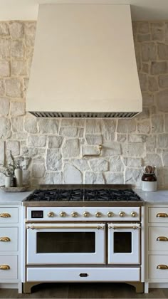 a stove top oven sitting inside of a kitchen next to white cabinets and counter tops