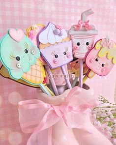 there are some cupcakes and donuts on sticks in a vase with a pink bow