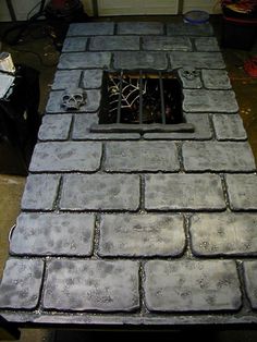 a fire place sitting on top of a cement floor next to a wall with a hole in it