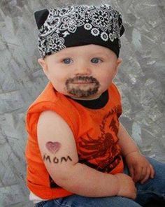 a baby wearing an orange shirt has a tattoo on his arm