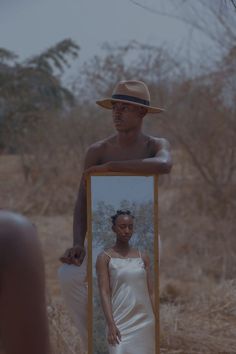 a man standing in front of a mirror next to a woman wearing a white dress