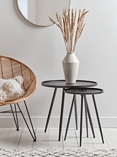 a white vase sitting on top of a table next to a black and white chair