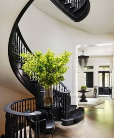 a black and white spiral staircase with flowers in a vase on the table next to it