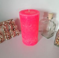 a pink candle sitting on top of a table next to some beads and other items