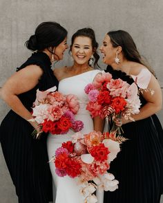 three bridesmaids in black and white dresses holding bouquets with red and pink flowers