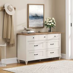 a white dresser sitting next to a wall with a painting on it's side