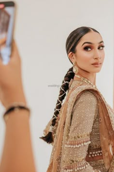 a woman with braids is taking a photo in front of a mirror while holding her cell phone