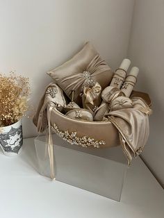 a vase filled with flowers and pillows on top of a shelf