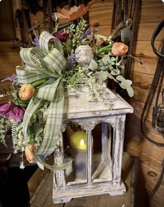 a white lantern with flowers and greenery on it