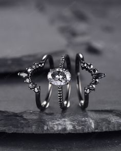 two rings with diamonds on them sitting on top of a piece of rock next to each other