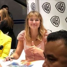 a woman sitting at a table with a man in front of her giving the thumbs up sign