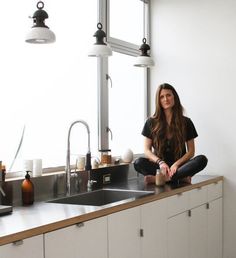 a woman is sitting on the kitchen counter