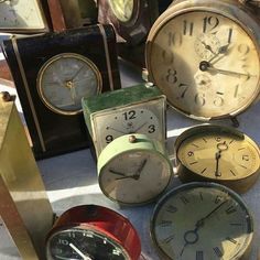 an assortment of old clocks on display at a flea market, including one with the time left