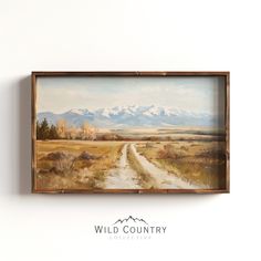 a painting hanging on the side of a wall next to a wooden framed sign that says wild country