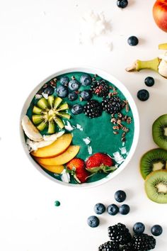 a bowl filled with fruit next to sliced kiwis