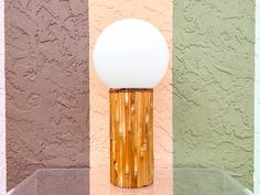 a lamp sitting on top of a glass table in front of a wall with multicolored walls