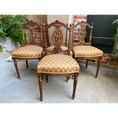 four antique chairs sitting next to each other in front of a brick wall and door