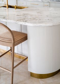 a white marble counter top sitting next to a wooden chair