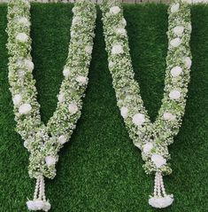 two rows of flowers and pearls are arranged in the shape of letters v on green grass