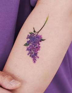 a woman's arm with a purple flower tattoo on the left side of her arm