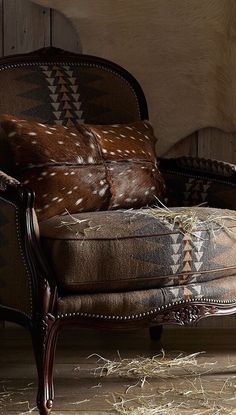 a chair that is sitting in front of a cowhide rug on the floor next to a wall