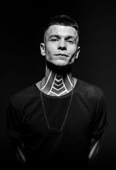 a man with tattoos on his neck standing in front of a black background