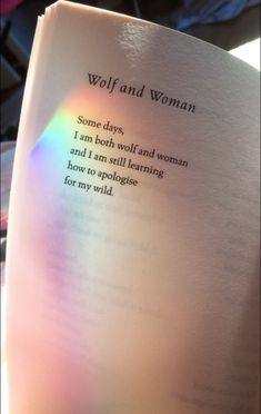 an open book with the words wolf and woman written in rainbow - hued light