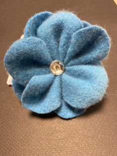 a close up of a blue flower on a brown surface with a button in the center