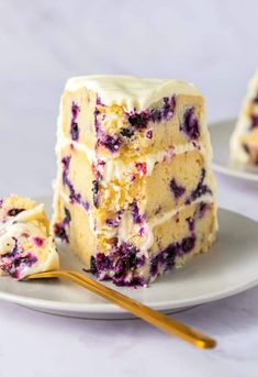 a piece of cake on a white plate with blueberries and cream cheese frosting