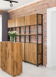 an empty room with brick walls and wooden shelves on the wall, along with a vase filled with flowers