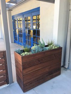 a large wooden planter with succulents in front of a blue door