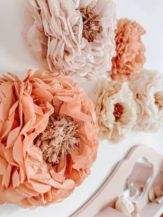 three paper flowers on a white surface next to silverware and utensils in front of them